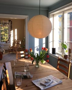 a dining room table with flowers in a vase on it and a lamp hanging from the ceiling