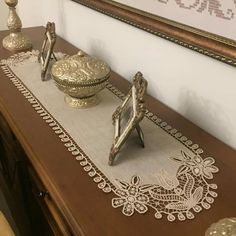 a table topped with two ornate items on top of a wooden table next to a mirror