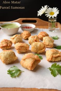 small appetizers on a tray with dipping sauces and flowers in the background