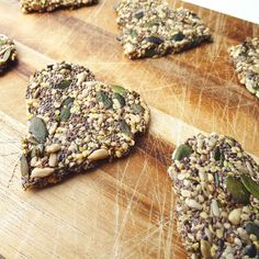 several pieces of granola on a wooden cutting board with leaves and seeds around them