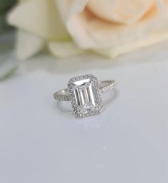 a close up of a diamond ring on a table with flowers in the back ground