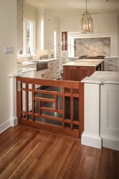 an open kitchen with wooden floors and white cabinetry on the walls, along with marble counter tops