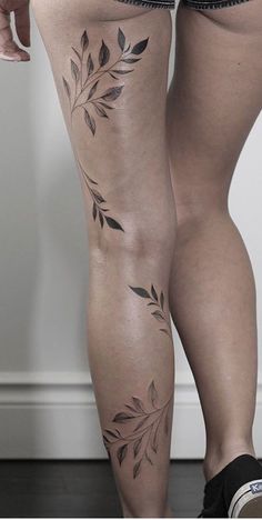 a woman's legs with tattoos on them and no shoes in front of her