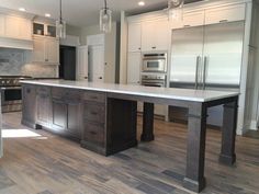 a large kitchen with an island in the middle and stainless steel appliances on both sides