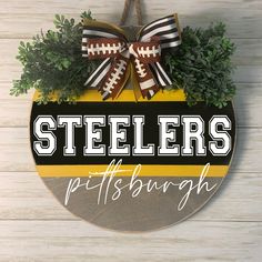 a pittsburgh football sign hanging on the side of a wooden wall with greenery around it