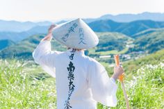 a man with a hat on his head walking through tall grass and holding a carrot