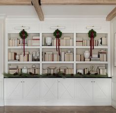 a white bookcase filled with lots of books and wreaths on top of it