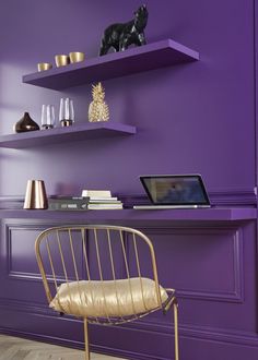 a purple room with shelves and a gold chair in front of the desk is an open laptop computer