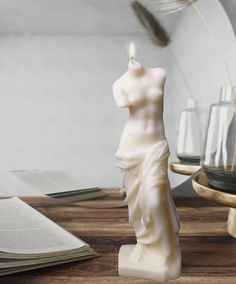 a white candle sitting on top of a table next to a book and glass vase