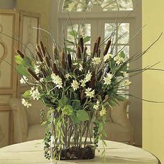 a vase filled with lots of flowers on top of a white table in front of a window