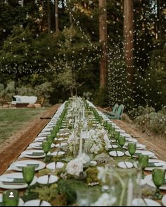 a long table is set with white plates and green napkins for an outdoor dinner