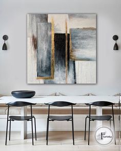 a dining room table with four chairs and a large painting on the wall above it