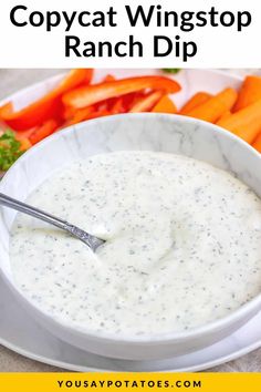 a white bowl filled with ranch dip surrounded by carrots and celery