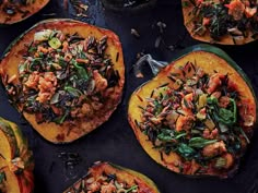 several stuffed squash with various vegetables and meats in them on a black table top