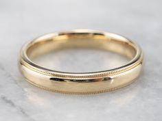 a gold wedding band on a marble surface