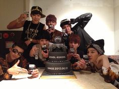 a group of young men taking pictures with their cell phones while sitting in front of a cake