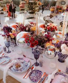 the table is set with plates, silverware and flowers