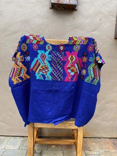 "Handwoven Guatemalan Huipil, Royal Blue Blouse with Bird Motifs, Vintage Chajul Textiles  Width: 23\" Length: 31\"  A woman may spend months weaving a single huipil when complex techniques or designs are required. Through the choices of design, material and finishing technique, information can be read about the weaver's birth-place, religious background, social position, weaving skill, and personality. Indigenous women can read the complex encoded messages in each other's huipiles at a glance.. Blue Short Sleeve Tops For Festivals, Blue Printed Crew Neck Blouse, Blue Folk Style Short Sleeve Blouse, Traditional Blue Short Sleeve Blouse, Blue Short Sleeve Folk Blouse, Traditional Blue Long Sleeve Tops, Traditional Long Sleeve Blue Tops, Blue Embroidered Folk Top, Traditional Blue Tops With Floral Embroidery