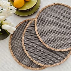 three round placemats sitting on top of a table next to plates and flowers