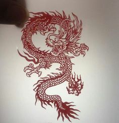 a drawing of a dragon on a piece of paper that has been drawn with red ink