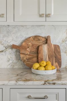 a wooden cutting board sitting on top of a counter next to lemons and a knife