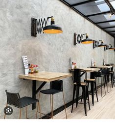 an empty restaurant with tables and stools in front of a wall mounted light fixture