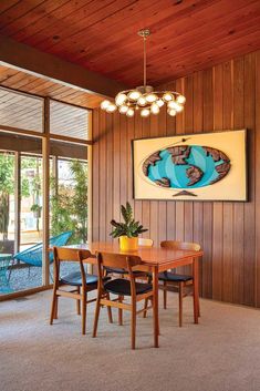 a dining room with wood paneling and a painting hanging on the wall above it