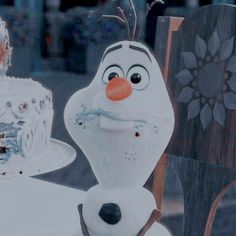 a frosted cake sitting on top of a table next to a frozen king figure