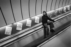 a person riding an escalator with posters on the wall