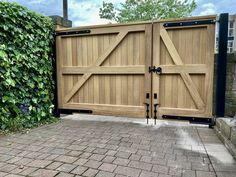 a large wooden gate with two black latches on each side and a brick walkway in front of it