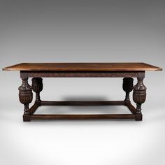 an old style wooden table with carved details on the top and bottom, against a gray background