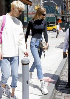 two people walking down the street with one person wearing white sneakers and another in blue jeans