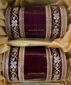 two red and gold bangles with white stones on them, sitting in a box