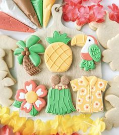 decorated cookies are arranged on a board with flowers and palm trees in the back ground