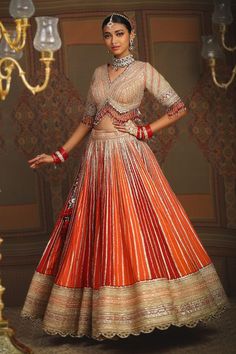 Rust maroon and orange toned attached cancan kalidar lehenga with chevron patterned gota, badla, dori embroidery and heavy tassel ornamentations. Paired with a half sleeves V neckline padded blouse with mughlai bloom gota jaal, badla, dori embroidery and dangling glass beads hem detail and heavily embellished scallop border georgette dupatta. - Aza Fashions Luxury Lehenga With Gota Work And Maxi Length, Gold Lehenga With Gota Work In Dola Silk, Transitional Orange Lehenga With Pallu, Orange Lehenga With Zari Work For Transitional Season, Elegant Orange Lehenga With Pallu Detail, Traditional Orange Gown With Zari Work, Elegant Orange Lehenga With Pallu, Floor-length Kundan Dupatta With Gota Work, Gold Gota Work Dola Silk Lehenga