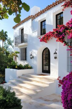 a white house with purple flowers on the steps