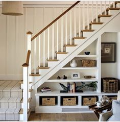 a white staircase with baskets under the bannister and bookshelves on either side