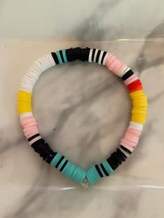 multicolored beaded bracelet on white marble counter with black, yellow, and pink beads