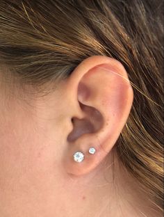 a close up of a person's ear with two diamond studs