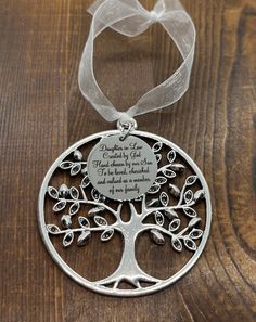 a silver tree ornament with a ribbon around it on a wooden table top