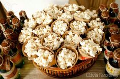 a bowl full of popcorn sitting on top of a table next to some bottles and spoons