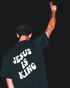 a man wearing a jesus is king t - shirt and holding a baseball bat in his right hand