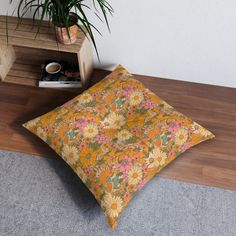 a pillow sitting on top of a wooden floor next to a potted plant