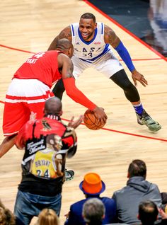 two men playing basketball on a court with people watching