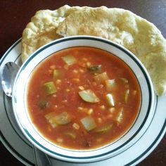 a bowl of soup and some pita bread on a table