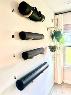 there are several yoga mats hanging on the wall next to a potted plant and window