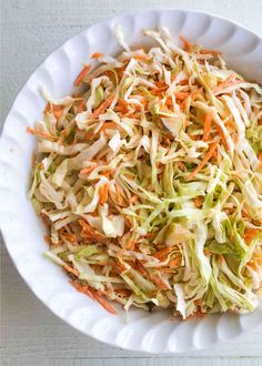 a white bowl filled with coleslaw and carrots on top of a table