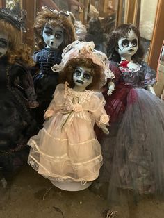 three creepy dolls sitting next to each other in front of a mirror on the floor