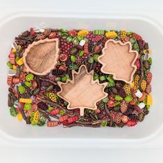 two wooden spoons sitting on top of a white container filled with candy and candies