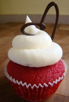 a red cupcake with white frosting and chocolate sprinkles on top